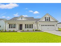 Charming home features a manicured lawn, inviting covered porch and a two-car garage at 5004 Shore Breeze Dr., Myrtle Beach, SC 29588