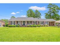 Charming brick home with a well-maintained lawn and manicured landscaping, exuding curb appeal and Southern charm at 1005 S Main St., Mullins, SC 29574