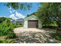 A detached garage features a brown door and light green siding, providing secure parking or storage at 127 Brown Pelican Loop, Pawleys Island, SC 29585