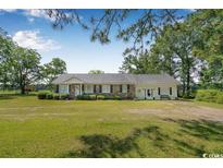 Charming ranch home with a well-maintained lawn, mature trees, and ample curb appeal on a sunny day at 12721 Pleasant Hill Dr., Hemingway, SC 29554