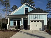 Charming light blue home featuring stone accents, a front-entry garage, and pristine landscaping at 3139 Tiger Tail Rd., Conway, SC 29526