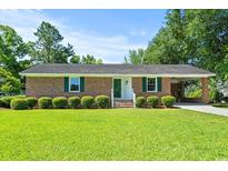 Charming brick home features a well-manicured front lawn and classic design, enhanced by lush green landscaping at 324 Camellia Ave., Marion, SC 29571