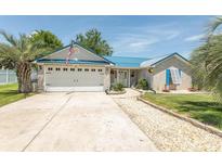Charming single-story home with a blue metal roof, a two-car garage, and beautifully landscaped front yard at 3879 Mallard Way, Little River, SC 29566