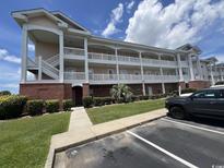 Three-story condo building with white railing balconies, brick facade, and manicured landscaping at 3965 Forsythia Ct. # 202, Myrtle Beach, SC 29588