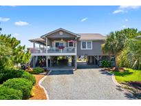 Charming coastal home with a stilt foundation, lush landscaping, and a spacious driveway at 401 Marlin St., Sunset Beach, NC 28468