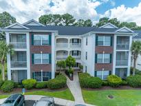 Attractive multi-story condo building with brick accents, white trim, well-maintained landscaping, and a walkway at 468 River Oak Dr. # 66D, Myrtle Beach, SC 29579