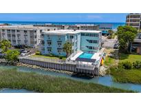 Aerial view of a light-blue multifamily building with a pool overlooking a waterway and the ocean at 6301 N Ocean Blvd. # 2B, North Myrtle Beach, SC 29582