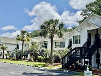 Charming condo exterior features white siding, black stairs, palm trees, and well-maintained landscaping at 850 Fairway Dr. # 904Ee, Longs, SC 29568