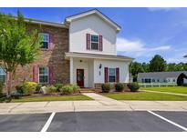 Charming two-story townhome with brick and siding, complemented by colorful landscaping and a well-maintained lawn at 8855 Radcliff Dr. Nw # 50B, Calabash, NC 28467