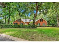 Charming brick home with a manicured lawn and mature trees providing shade and privacy at 241 Black Duck Rd., Pawleys Island, SC 29585