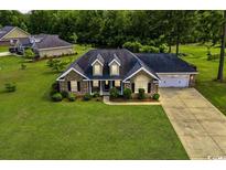 Beautiful brick house with manicured lawn and shrubs, complemented by an attached two-car garage and charming dormers at 301 Farmtrac Dr., Galivants Ferry, SC 29544