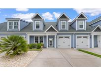 Charming blue two-story townhouse featuring a well-manicured lawn and attached garages under a bright blue sky at 413 Goldenrod Circle # 2B, Little River, SC 29566