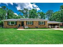 Charming brick home featuring manicured front lawn, solar panels, and covered carport at 4189 Schoolhouse Circle, Little River, SC 29566