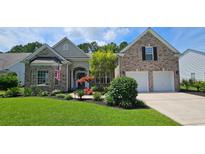 Beautiful brick home featuring a two-car garage, manicured lawn, and colorful landscaping at 6400 Longwood Dr., Murrells Inlet, SC 29576