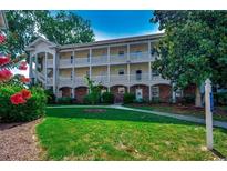 Three-story condominium building with white railings, brick accents, and lush green lawn at 695 Riverwalk Dr. # 101, Myrtle Beach, SC 29579