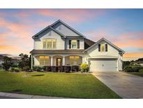 Charming two-story home with white siding, inviting front porch, manicured lawn, and attached two-car garage at 932 Abernathy Place, Surfside Beach, SC 29575