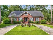 Charming single-story brick home featuring a circular driveway and a beautifully landscaped front yard with a water feature at 4691 Mill Pond Rd., Murrells Inlet, SC 29576