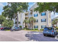 Condo building exterior with light-yellow siding, white trim, green shutters, and palm trees at 601 Hillside Dr. N # 3926, North Myrtle Beach, SC 29582