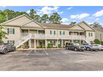 Inviting two-story condo building with light beige siding, balconies, green shutters, and ample parking spaces at 160 Lazy Willow Ln. # 202, Myrtle Beach, SC 29588
