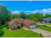 Well-maintained brick home with a two-car garage, lush lawn, and mature trees under a bright blue sky at 2454 Glen Dr., Little River, SC 29566