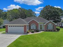 Charming brick home with a well-manicured lawn, attached two car garage, and colorful landscaping at 3888 Stillwood Dr., Myrtle Beach, SC 29588