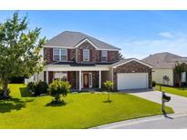 Charming two-story brick home featuring a well-manicured lawn and an attached two-car garage at 445 Mooreland Dr., Myrtle Beach, SC 29588