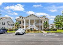 Inviting condo with covered front porch and white railings, landscaping, and ample parking at 447 Mahogany Dr. # 102, Murrells Inlet, SC 29576