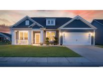 Charming single-story home with a covered front porch, lush lawn, and attached two-car garage at sunset at 567 Hickman St., Myrtle Beach, SC 29575