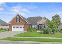 Charming brick home featuring a well-manicured lawn, attached garage, and beautiful landscaping at 8708 Coosaw Ct., Myrtle Beach, SC 29577