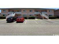 Condo exterior with covered stairs, parking and manicured bushes in front of building at 1101 2Nd Ave. N # 306, Surfside Beach, SC 29575