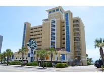 Attractive, multi-story, tan hotel exterior featuring bright blue accents and palm trees near the ocean at 1200 N Ocean Blvd. # 211, Myrtle Beach, SC 29577