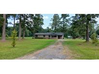 Quaint single-story brick home with a charming front porch surrounded by mature trees at 1206 French Rd, Mullins, SC 29574