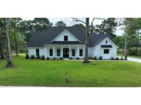 Inviting two-story modern farmhouse exterior with white siding, dark roof, manicured lawn, and columned front porch at 1464 Hawthorn Dr., Pawleys Island, SC 29585