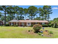 Charming single-story brick home with well-manicured front yard and mature trees at 207 Green Lake Dr., Myrtle Beach, SC 29572