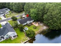 An aerial view showcasing a home with a pond, patio, and lush green landscaping backing up to woods at 2611 Ringneck Trail, Myrtle Beach, SC 29588
