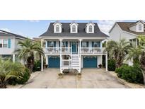 Charming coastal home boasts a double porch, blue shutters, and well-maintained landscaping with palm trees at 304 62Nd Ave N 62Nd Ave. N, North Myrtle Beach, SC 29582