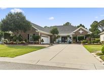 Charming brick home featuring a spacious driveway, manicured lawn, and beautifully landscaped garden beds at 5904 Bridlewood Rd., North Myrtle Beach, SC 29582
