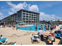 Resort style pool featuring many people enjoying a swim, lounge chairs, tables and multi-story living at 5905 S Kings Hwy. # 416 A, Myrtle Beach, SC 29575
