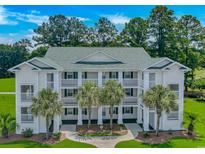 Inviting condo building featuring multiple stories, balconies, and lush landscaping with palm trees at 650 Tupelo Ln. # 5-F, Longs, SC 29568