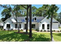 Charming white farmhouse with a black roof and lush landscaping at 974 Crooked Oak Dr., Pawleys Island, SC 29585