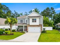 Charming two-story home featuring manicured lawn, inviting porch, and attached two-car garage at 1007 Oak Marsh Ln., North Myrtle Beach, SC 29582