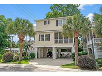 Inviting two-story home with well-maintained landscaping, palm trees, and convenient ground-level parking at 1011 Sable Palm Way, Surfside Beach, SC 29575