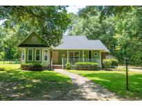 Charming green home featuring a welcoming front porch and well-manicured lawn and landscaping at 309 Otter Run Rd., Pawleys Island, SC 29585