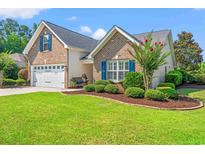 Charming brick home with well-manicured lawn and inviting curb appeal, featuring a two-car garage and blue shutters at 312 Caldera Ct., Murrells Inlet, SC 29576