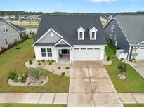 Beautiful exterior view of home with landscaped front yard, two-car garage, and a dark roof at 5087 Sundrop Ln., Little River, SC 29566