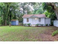Charming single-story home with a well-maintained front yard and a shed, nestled among mature trees at 609 3Rd Ave. N, Myrtle Beach, SC 29577