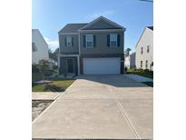 Two-story home featuring a two-car garage, concrete driveway, tidy lawn, and lush plantings under a brilliant blue sky at 6619 Colonial Dr., Myrtle Beach, SC 29572
