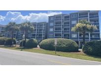 Low angle view of a well-kept condo building with palm trees and fresh landscaping on a sunny day at 812 S Ocean Blvd. # B-3, Surfside Beach, SC 29575