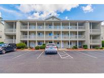 Condo building exterior with balconies, ample parking and manicured landscaping on a partly cloudy day at 1450 St. George Ln. # E, Myrtle Beach, SC 29588