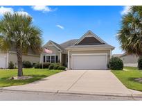 Charming single-story home featuring an attached two-car garage and a well-manicured front lawn with palm trees at 155 Palmetto Green Dr., Longs, SC 29568